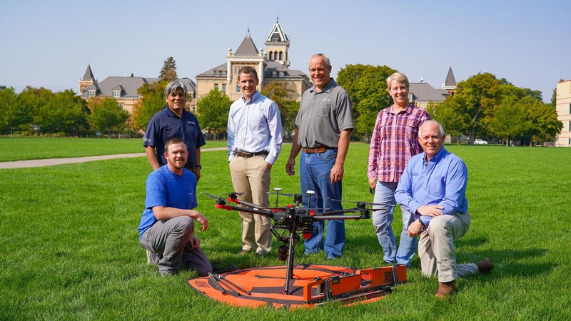 USU's cherry research team poses with a UAV underneath Old Main on the Quad.