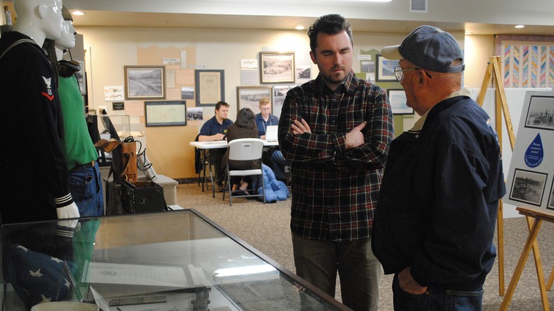 A USU students speaks to a war veteran about artifacts