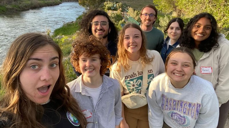 A group of students posing for a picture along a stream.