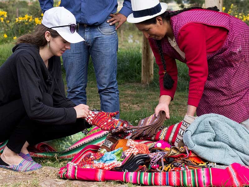 Huntsman student with a woman looking at textiles in South America.