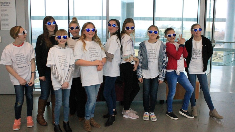 Sunglasses wearing elementary school students lined up in Huntsman Hall.