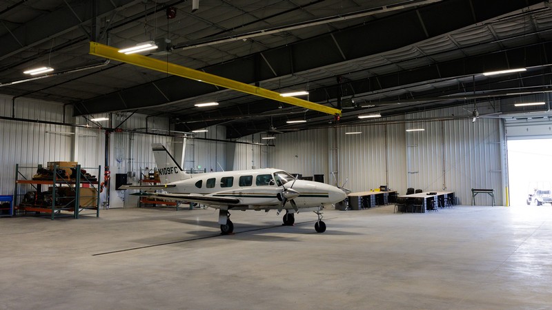 small white plane is inside an aviation hangar
