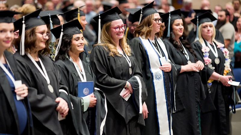 Students at USU Southwest stand in cap and gown