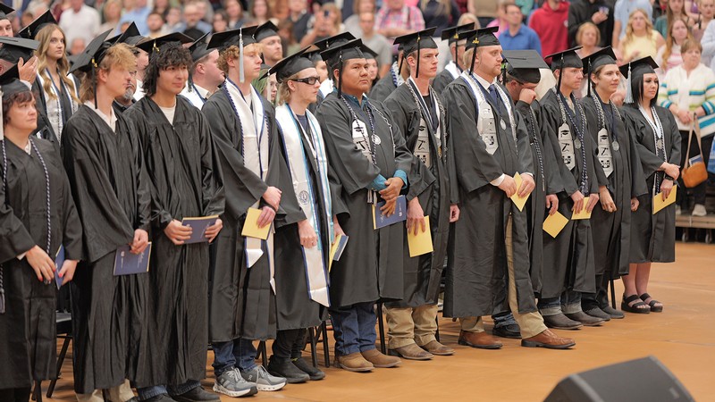 A group of graduates stand in applause.