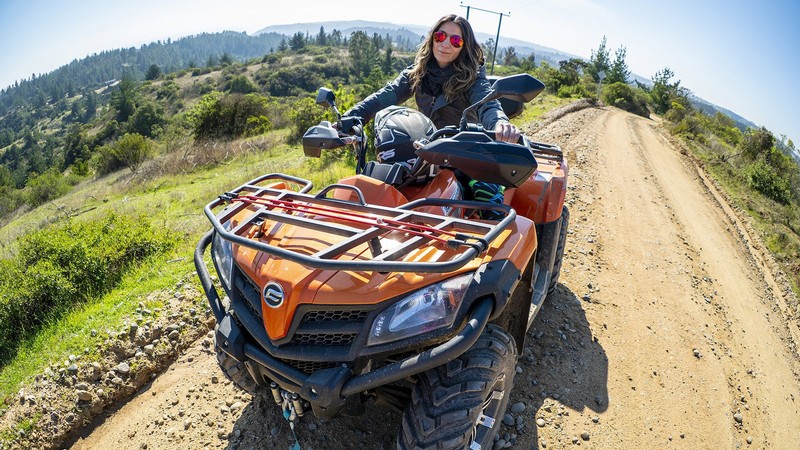 Woman riding an OHV on a dirt road in the wilderness.