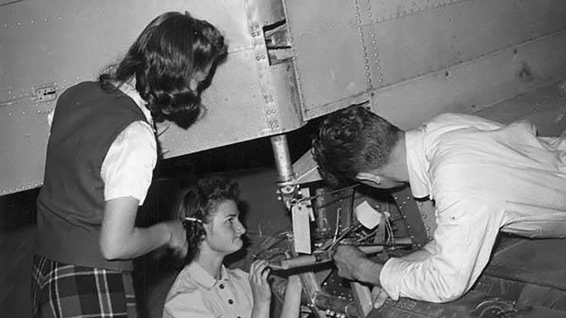 Two female and one male student working on the rear of an airplane, 1940s.