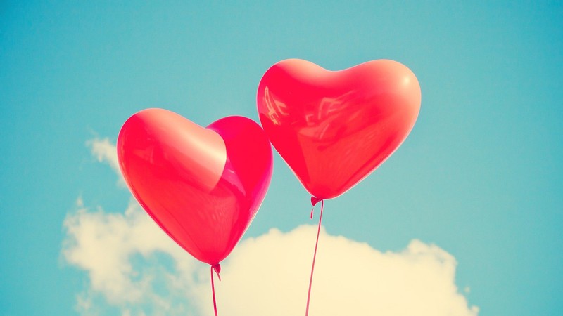 two heart-shaped balloons floating in the air.