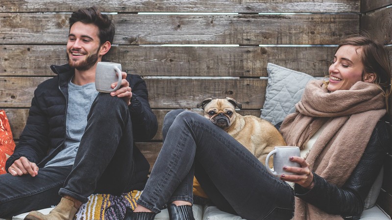 A couple relaxing on an outside deck with their dog.