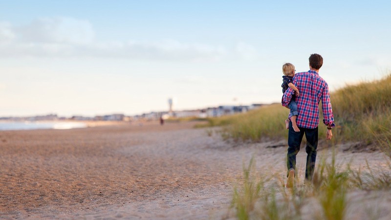 father and son walking on a beach.