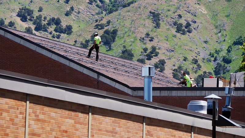 Construction workers installing solar panels on top of the fine arts visual building.