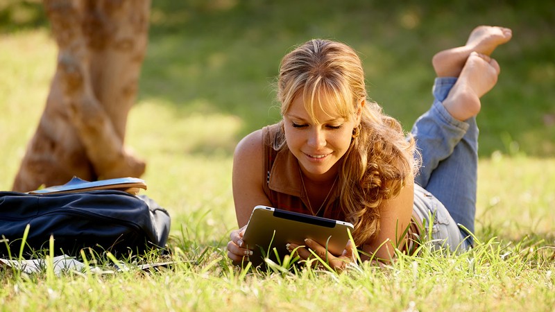 girl studying on her tablet in the grass.