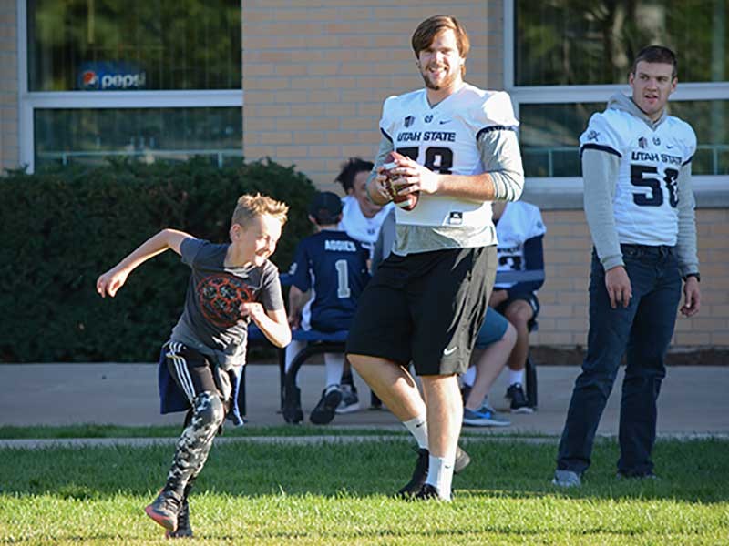USU football players with Sound Beginnings students
