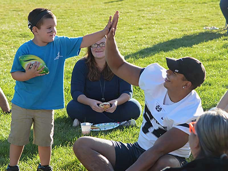 USU football players with Sound Beginnings students