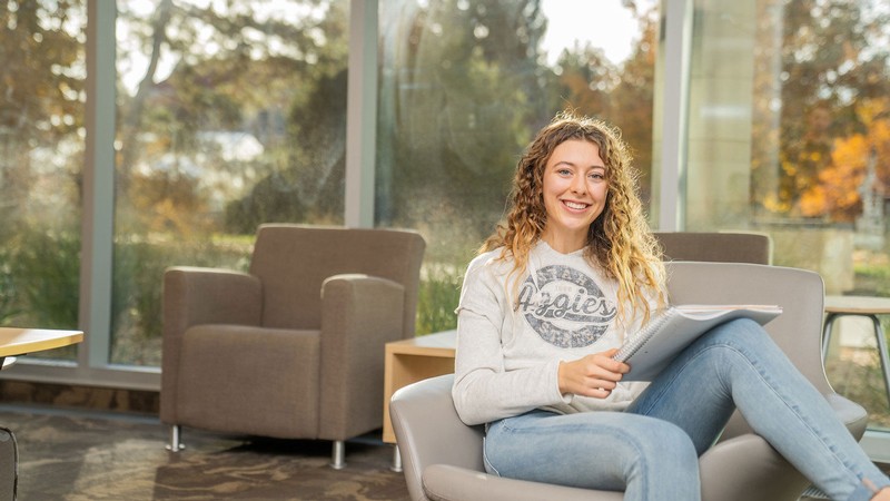 Woman student sitting in a chair on campus.