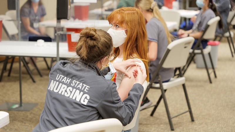 USU student receiving a vaccine from a USU Nursing student.