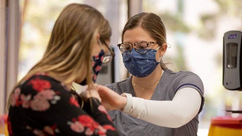 USU student receiving a vaccine from a USU Nursing student.