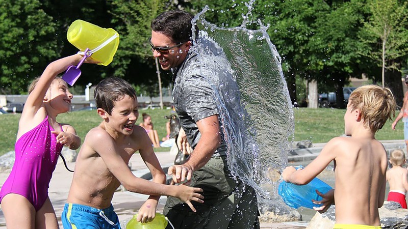 Family having a water fight in a park.