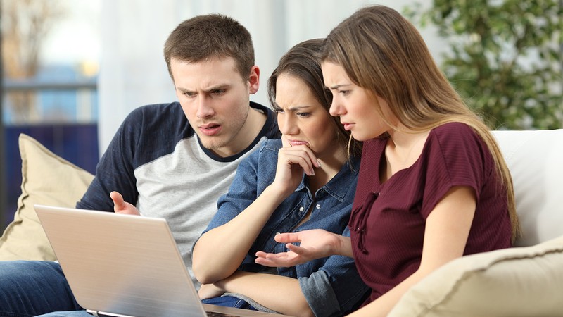 Mother with her two children looking in shock at a computer screen.