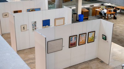 Paintings hang on an exhibit wall at the Merrill-Cazier Library at USU in Logan.