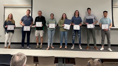 Student researchers stand in a line and hold certificates.