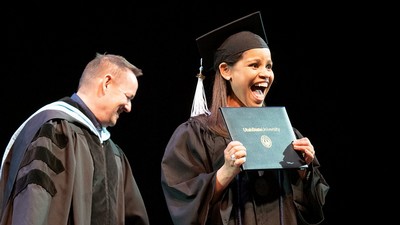 Woman smiles holding diploma cover