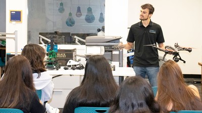 Person shows drones to group of teens.