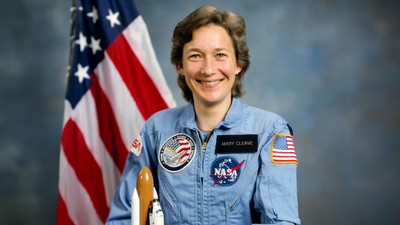 Mary Cleave wearing astronaut uniform with American flag in the background