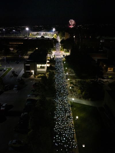 Students holding lights walking from the Spectrum to the Quad.