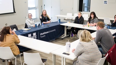 A group of people sit at a table in a discussion.
