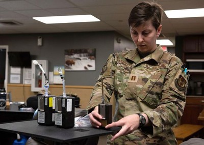 A person in military fatigues handling scientific instruments.