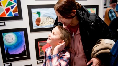 A woman and a child looking at art in a gallery.