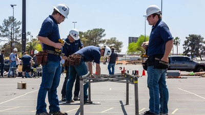 Students building a small steel bridge in a parking lot.