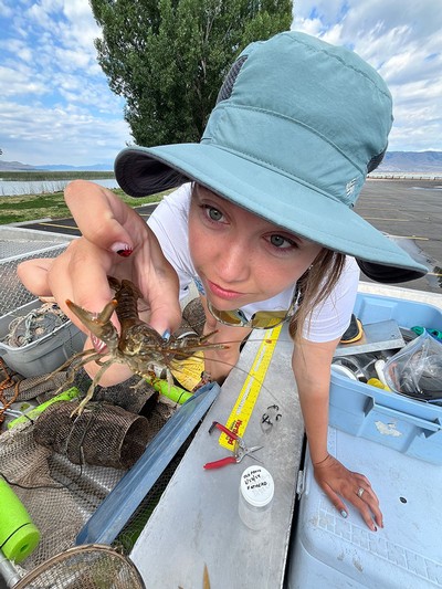 A researcher holding an invertebrate with pincers toward the camera.