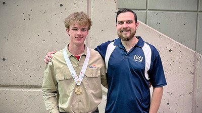 A student and a professor posing with an award medal.
