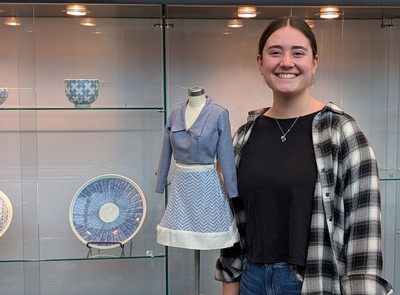 Rachel Godfrey posing next to a half-size dress and blue dishes.
