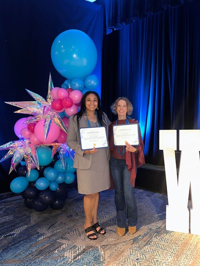 Two people holding awards at a ceremony.