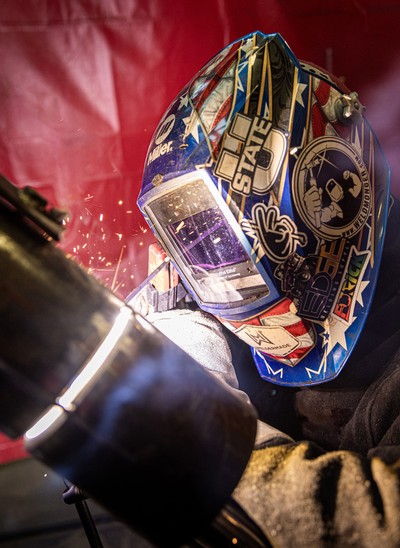 A person in a welding mask using TIG welding equipment.
