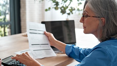 A woman looking at a bill and using a calculator.