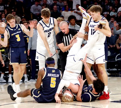 Karson Templin upside down in a pile of players on a basketball court.