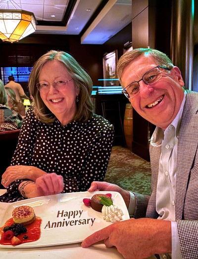 Larry and Laurie Walther at a restaurant. Text on plate reads "happy anniversary."
