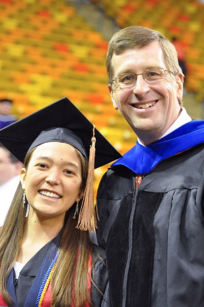 Larry Walther and Jill Aoki in graduation robes in the USU Spectrum.