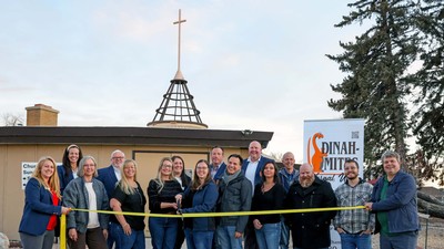 People cut a ribbon in front of a building.