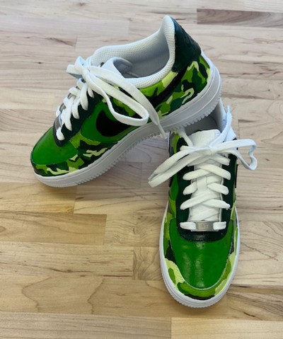An image of Nike sneakers with a custom green camo design.