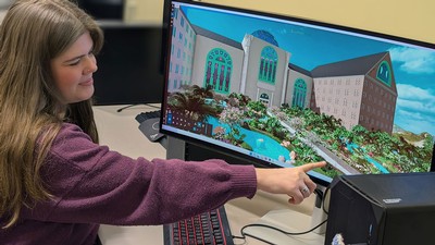 A student pointing to a landscape design on a computer monitor.