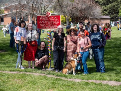 People pose in front of a historical marker for Mendon May Day.