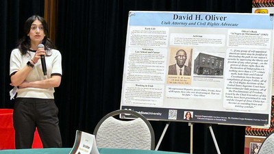 Yasamin Osqueezadeh speaking next to a research poster on David H. Oliver.