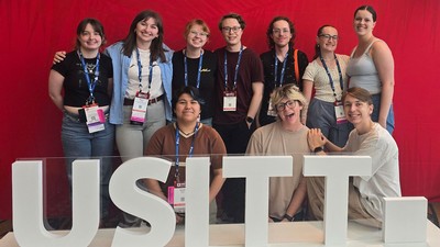 A group photo of students. Sign reads "USITT."