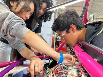 Students working on a kit vehicle's wiring.
