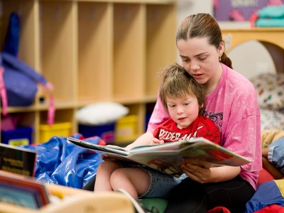 A person reading to a child in their lap.