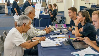 Researchers speaking with older adults at an event.